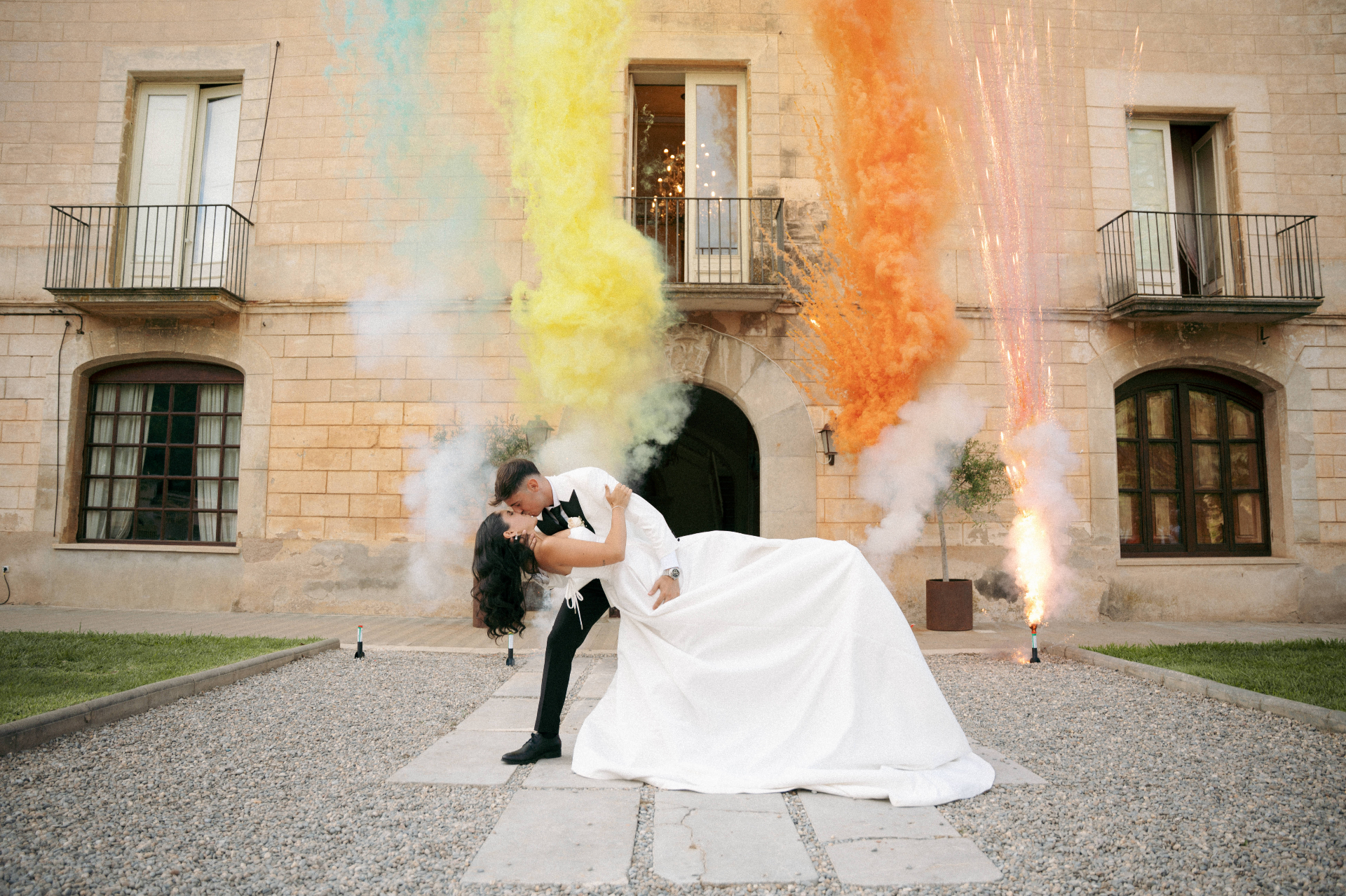 Andrea y Marc besándose entre humo de colores y fuegos artificiales el día de su boda