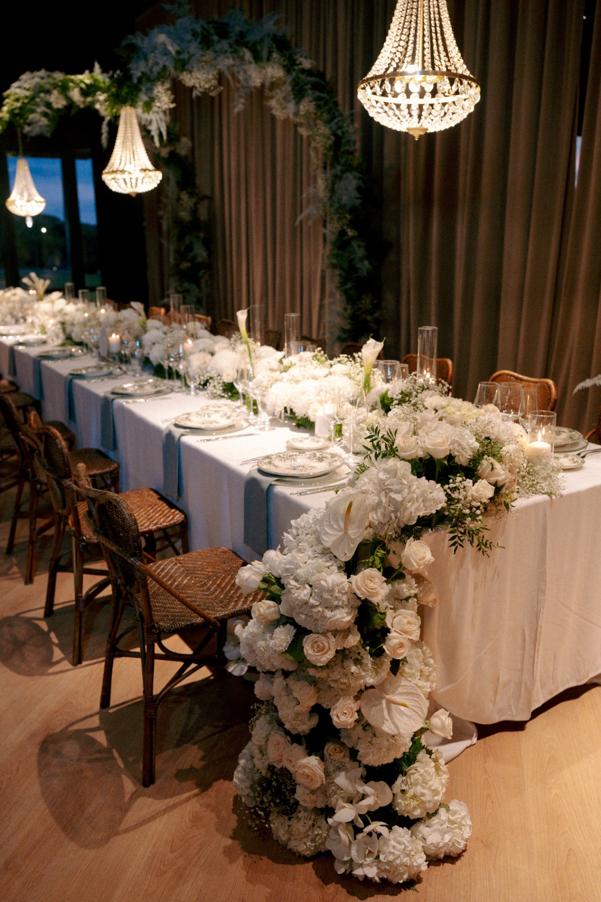 Mesa imperial decorada con flores blancas y lámparas de cristal en un banquete de boda elegante